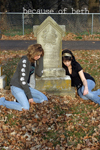 Two young women lying against a gravestone, sad